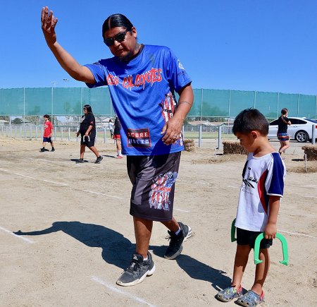 Robert Jeff shows son Thempsa the proper technique for throwing horseshoes.